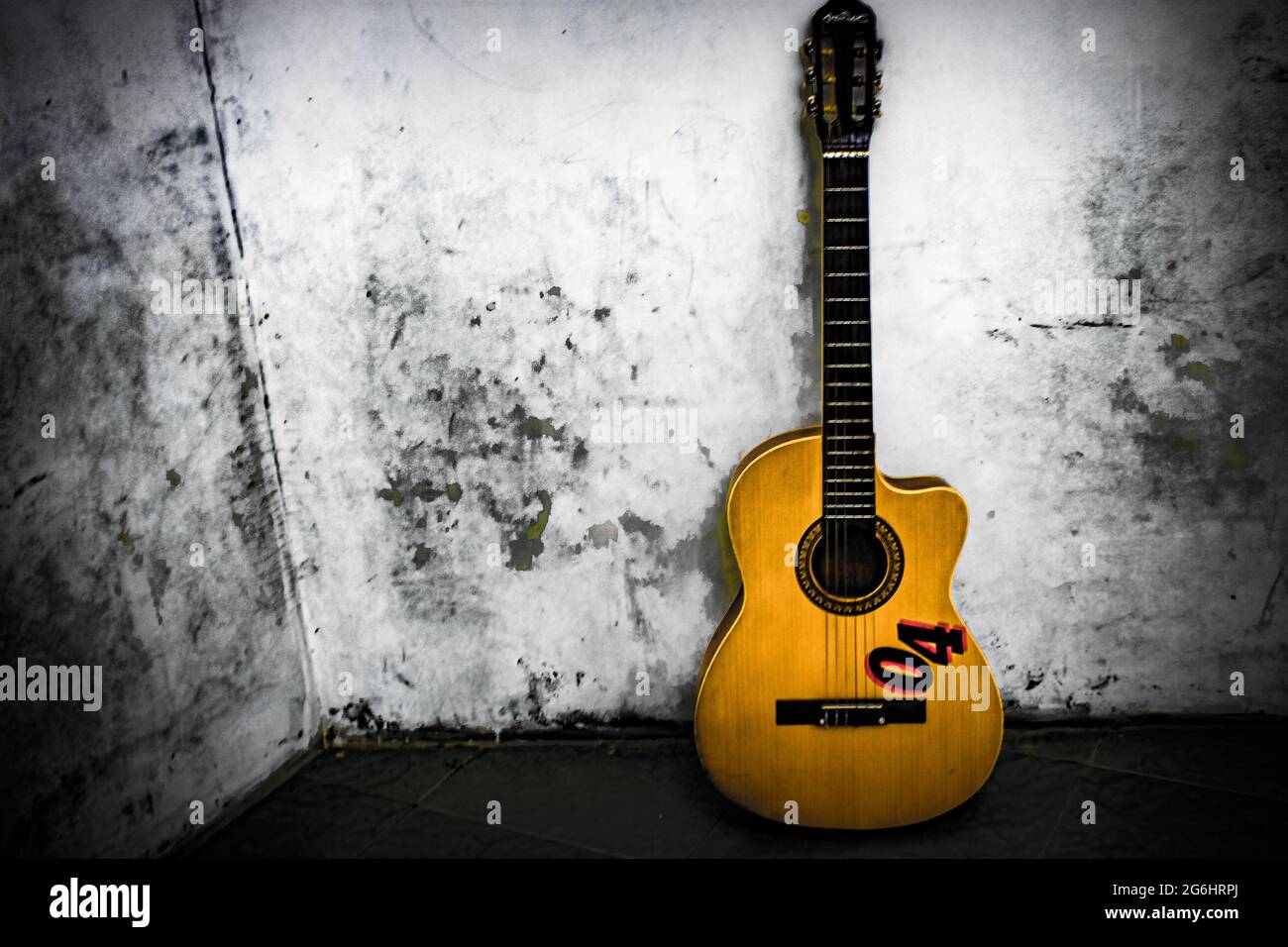 Guitar leaning against a white wall Stock Photo