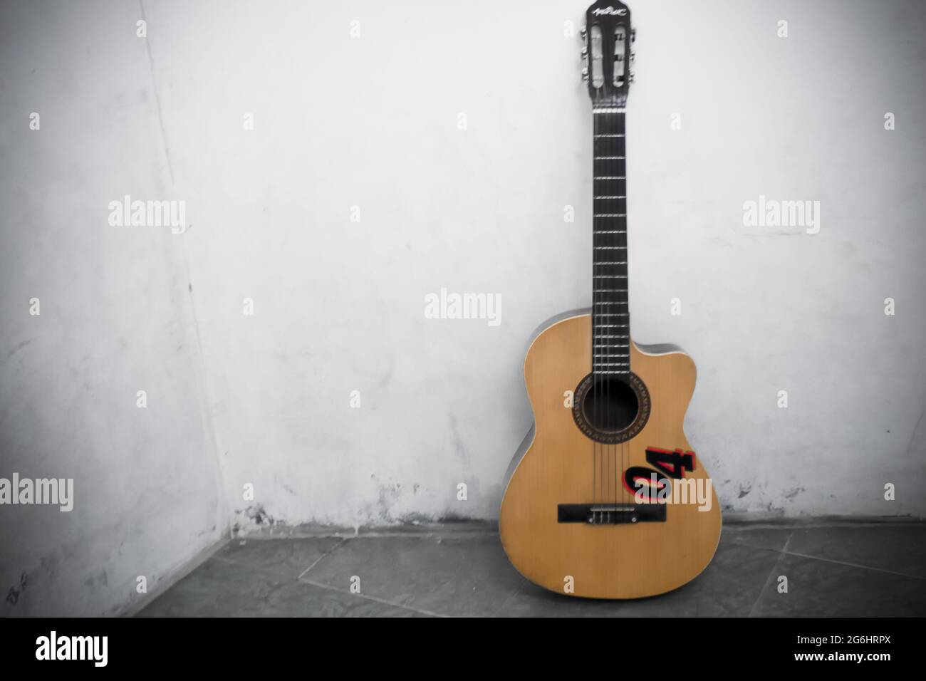 Guitar leaning against a white wall Stock Photo
