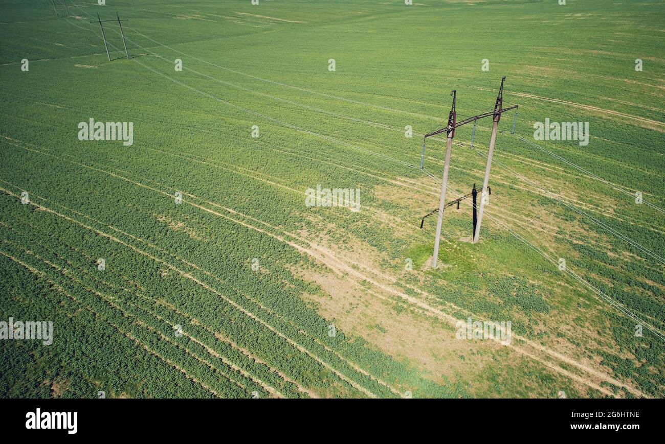 High voltage electric line towers on green meadow background aerial above top view Stock Photo