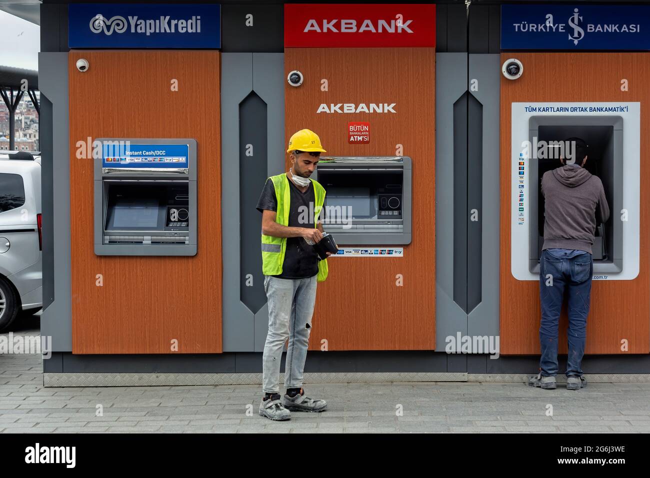 Construction worker in front of Yapikredi, Akbank, Isbank bank ATM s, after withdrawing monthly paycheck. Karakoy, Istanbul - Turkey. Stock Photo
