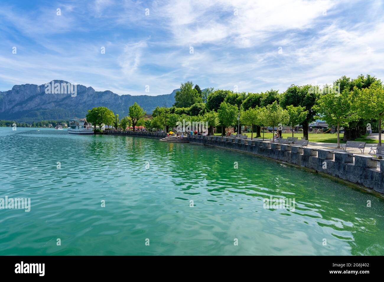 06.05.2021 - Mondsee, Austria: Mondsee with mountains and the beautiful promenade with people and ships Stock Photo