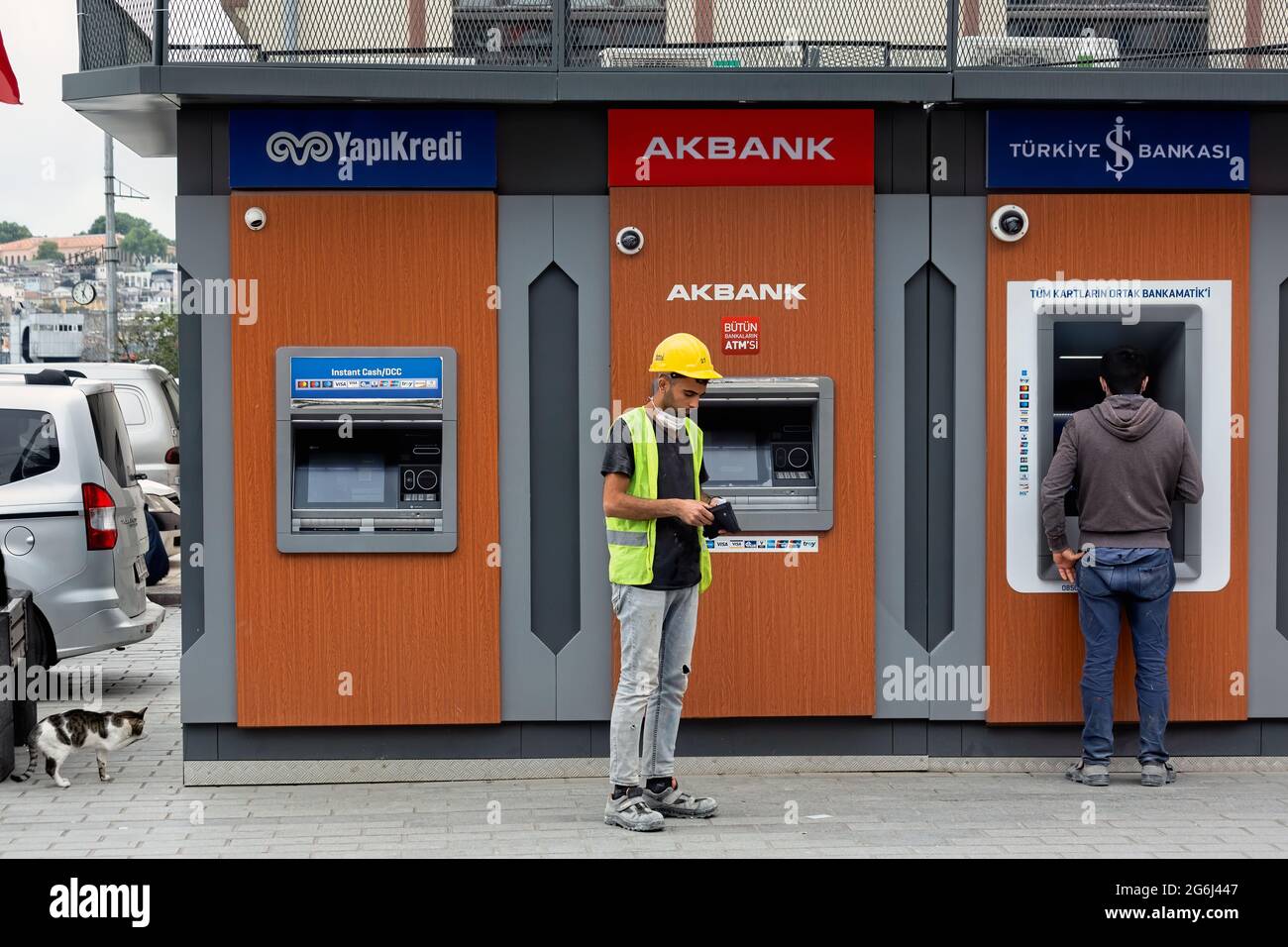 Construction worker in front of Yapikredi, Akbank, Isbank bank ATM s, after withdrawing monthly paycheck. Karakoy, Istanbul - Turkey. Stock Photo