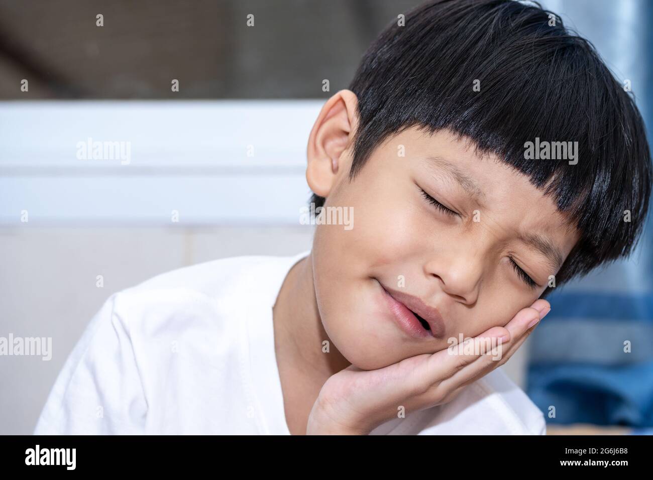 Asian little boy is doing a terrible toothache. Portrait a little boy suffering from toothache. Oral Care Concepts Stock Photo