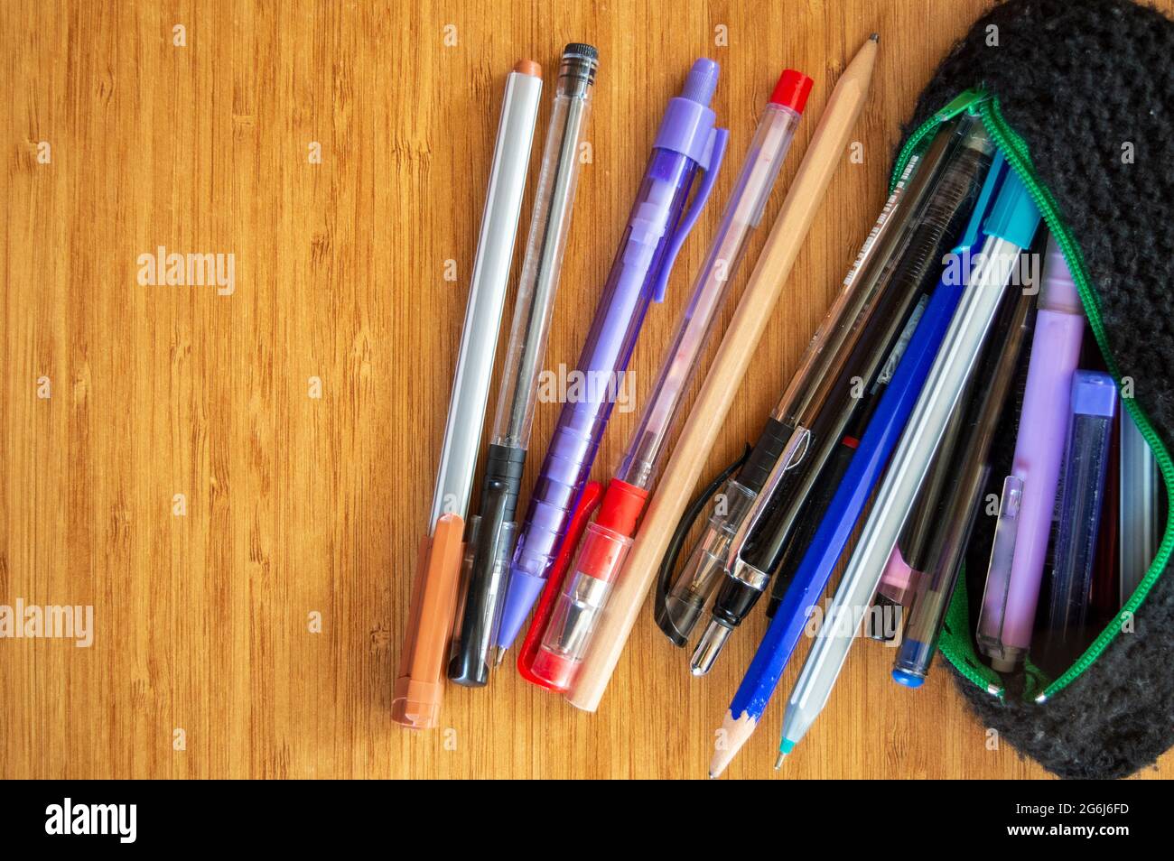 Lots of different pen and pencils spreading through black pencil holder on wooden table.Study for exams and education concept. Pile of pencils Stock Photo