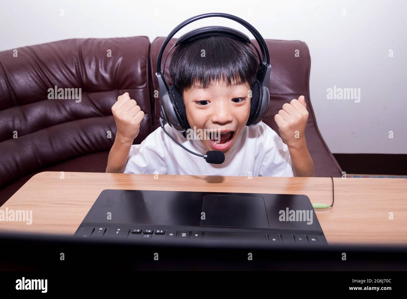 Very happy child playing game online with laptop stay at home. Asian boy student online learning class study online video call teacher. Stock Photo