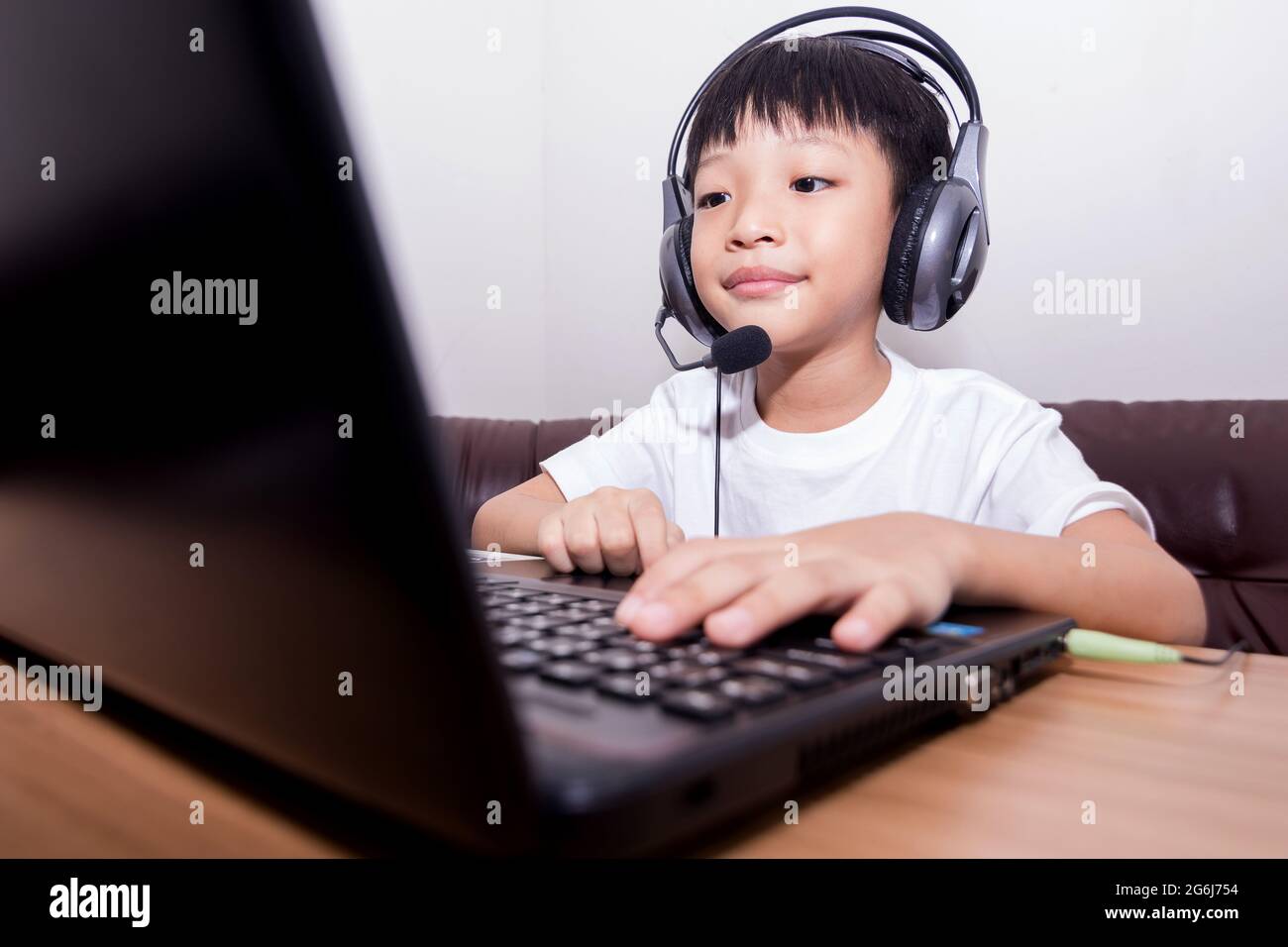 Asian boy student online learning class study online video call teacher. Happy child playing the game online with laptop stay at home. Stock Photo
