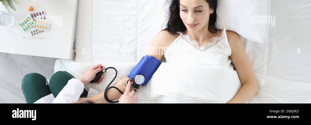 Nurse measures blood pressure of woman in bed Stock Photo Alamy