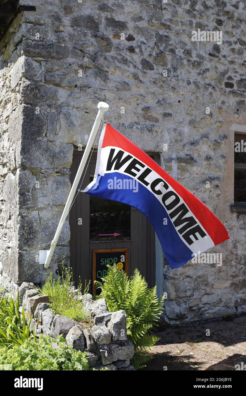 Red, White and Blue WELCOME flag blowing in the wind. Photographed from a public road. Stock Photo