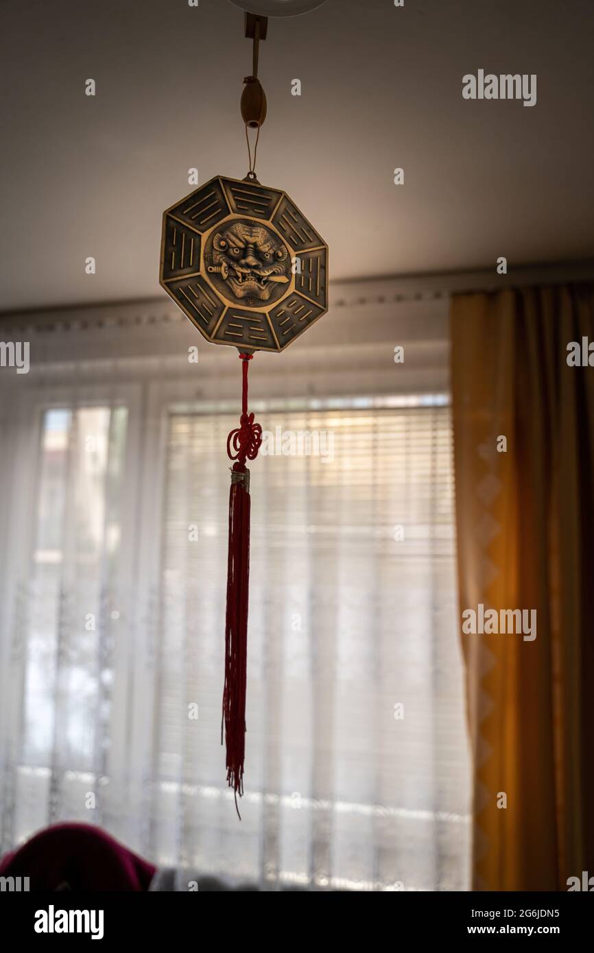 Octagon Bagua Mirror Feng Shui hanging from a roof inside a room against curtains- powerful cure to protect against negative energy and create good fo Stock Photo