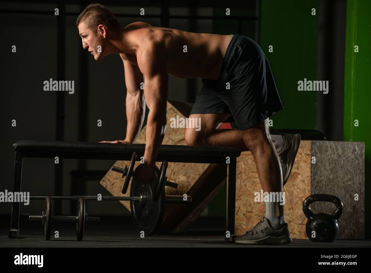 Good looking young man doing triceps dumbbell kickback exercises with