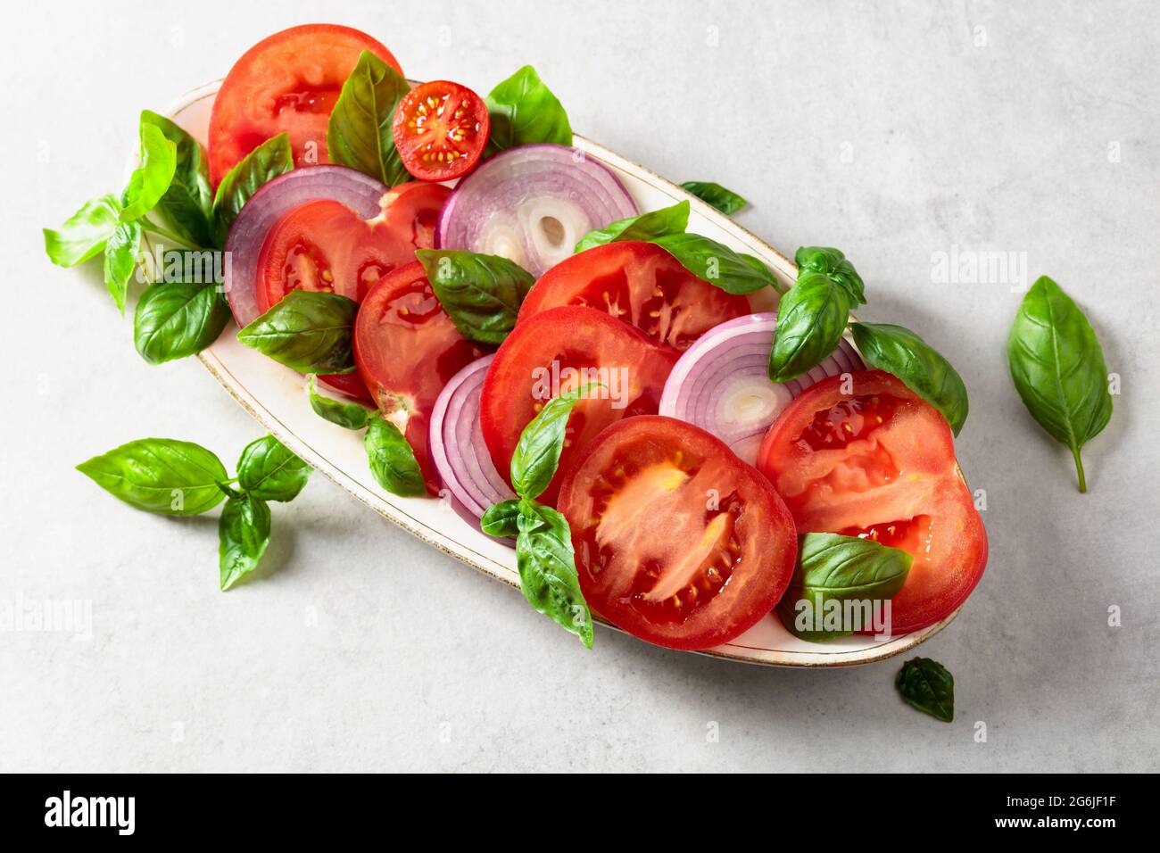 Salad with tomatoes, basil, and red onion on a kitchen table Stock ...