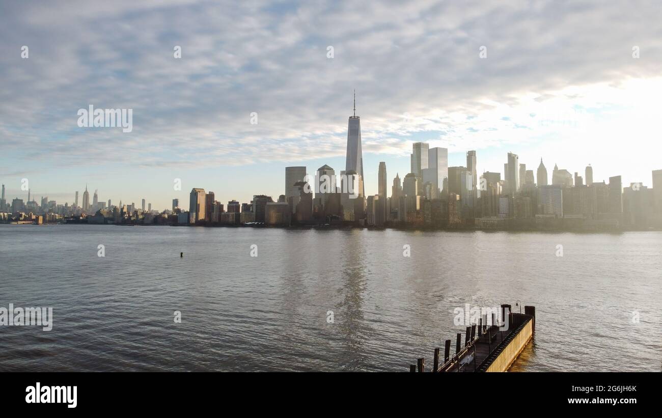 Panorama of the New York skyline with Freedom Tower, from New Jersey with a dock out into the Hudson River at sunrise. Stock Photo
