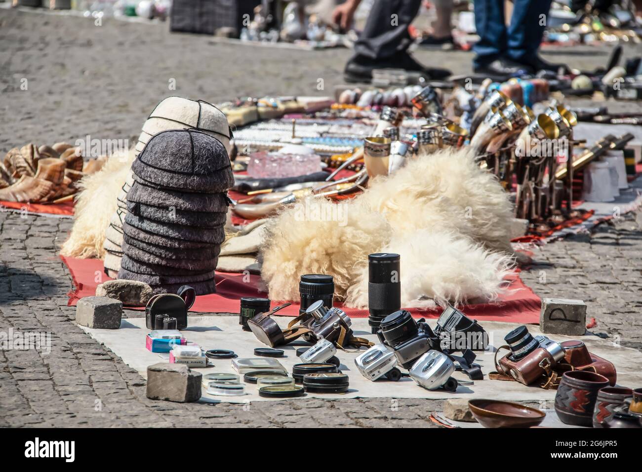 Goods spread out to sell at famous Dry Bridge Market flea market in Tbilisi Georgia include old camera equipment and traditional fur hats and drinking Stock Photo