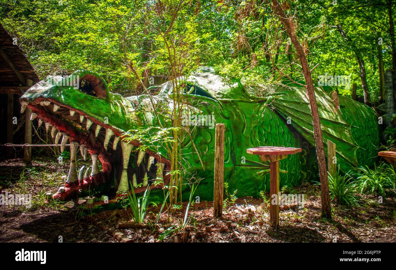 Green scaly dragon in woody park where children can play inside Stock Photo