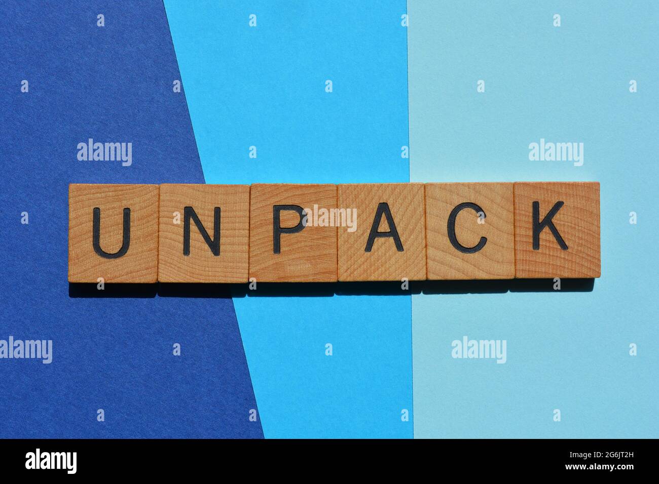 Unpack, word in wooden alphabet letters isolated on blue background as banner headline Stock Photo