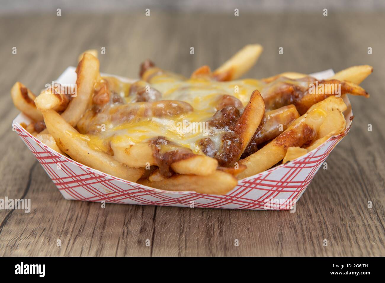 Melted cheese smothers this entire boat of chile cheese french fries as a very filling side dish. Stock Photo