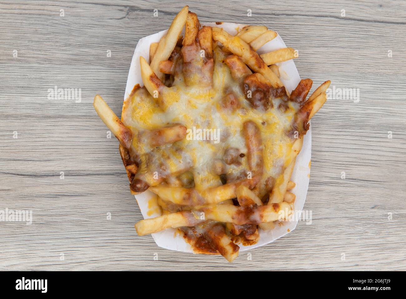 Overhead view of melted cheese smothers this entire boat of chile cheese french fries as a very filling side dish. Stock Photo