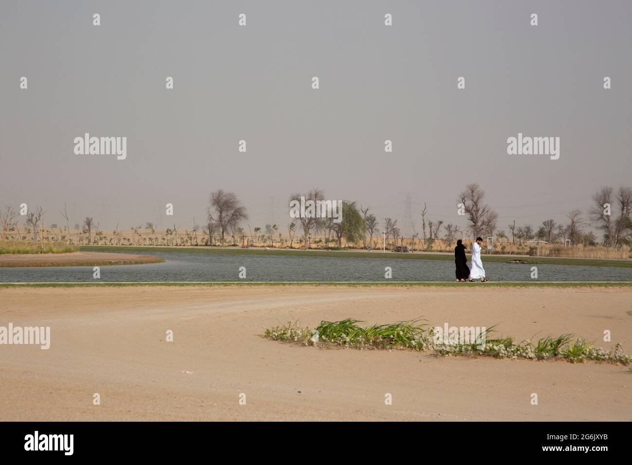 A couple walks along the Love Lakes in Al Qudra, Dubai, UAE. --- The Love Lakes Dubai are made up of two artificial heart shaped lakes. The lake is so Stock Photo