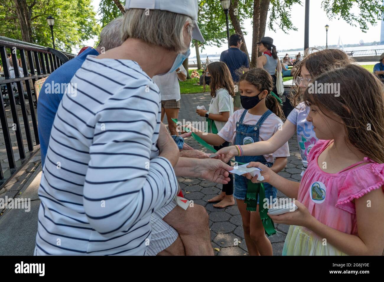 NEW YORK, NY – JULY 05: Children hand out stickers and green ribbons during a rally in Rockefeller Park to protest Gov. Andrew Cuomo's plans for a COV Stock Photo