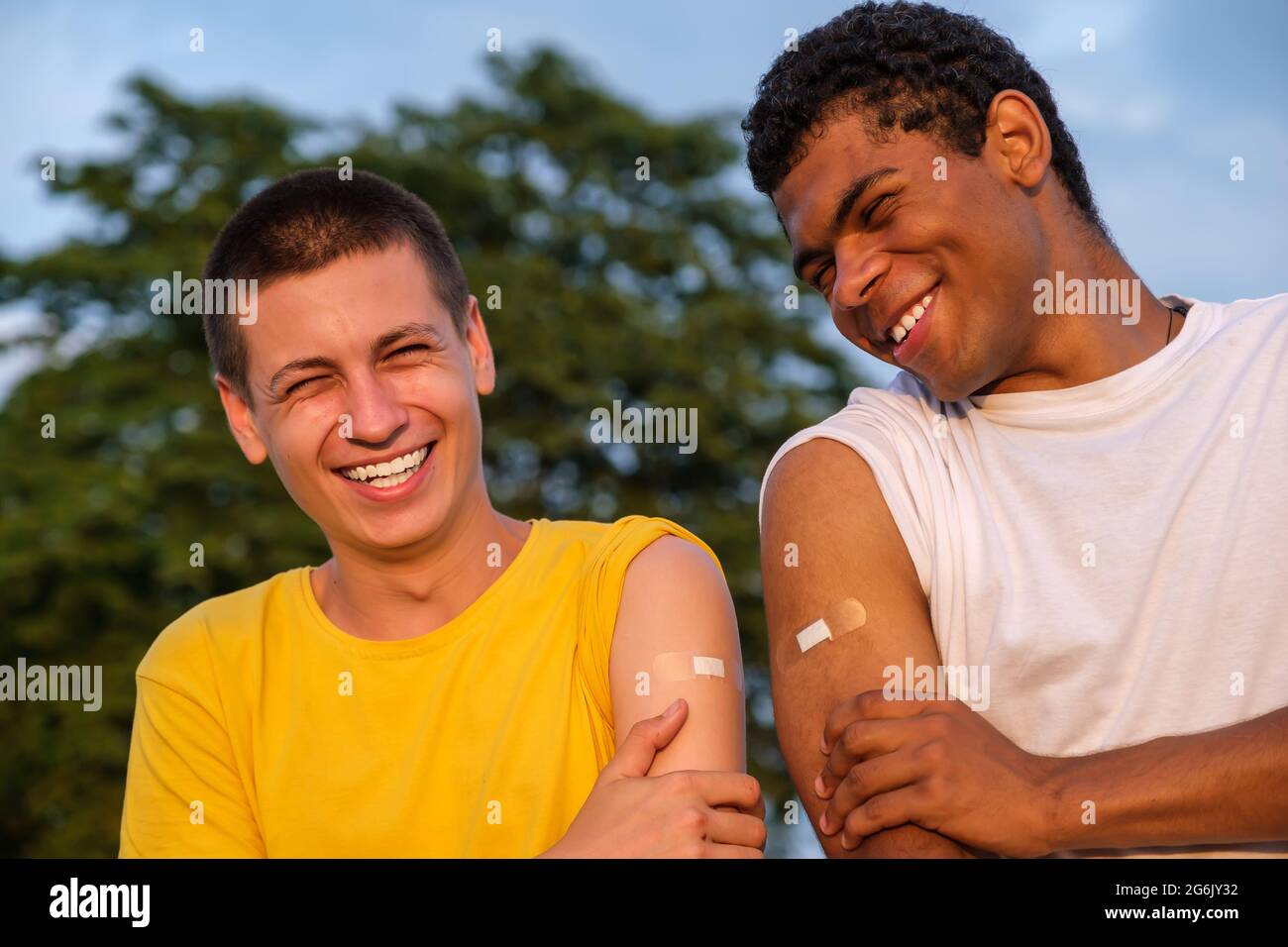 Two african american and caucasian friends showing their hands after vaccination Stock Photo