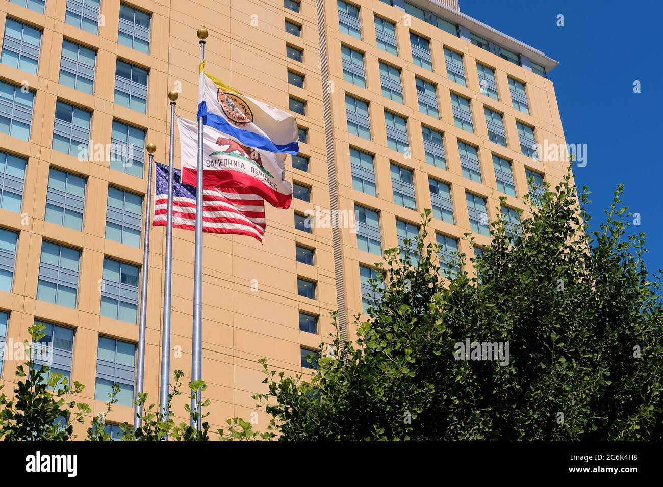 Fluttering flags of the United States, California, and City of San Jose flying in the wind on a sunny day in Silicon Valley's San Jose, California. Stock Photo