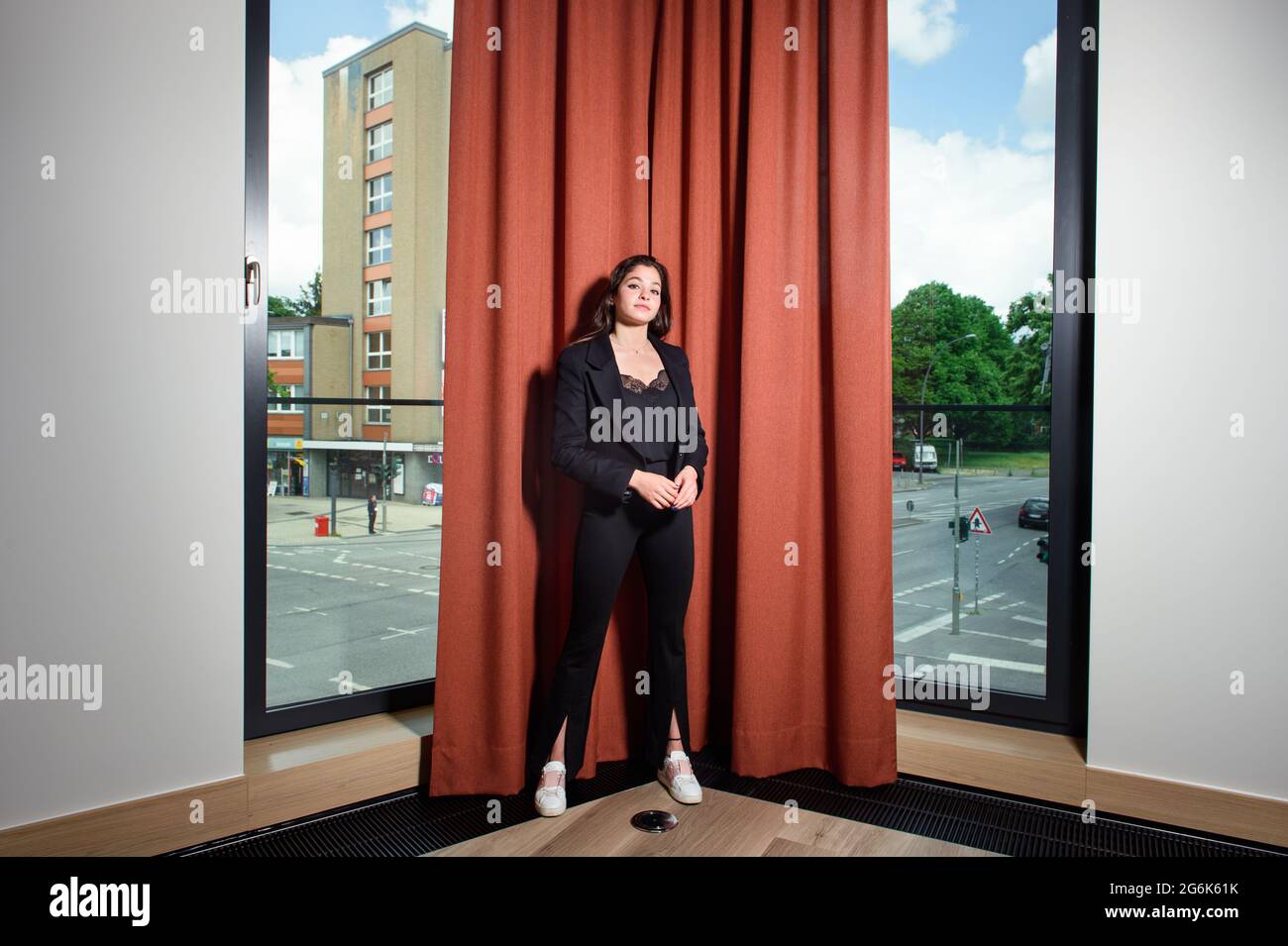 Hamburg, Germany. 12th June, 2021. Yusra Mardini, a swimmer, stands in front of a red curtain in the lounge of a Hamburg hotel. An intersection in Hamburg can be seen in the background. (to dpa "Freigeschwommen: Yusra's long journey from refugee to silent heroine") Credit: Gregor Fischer/dpa/Alamy Live News Stock Photo
