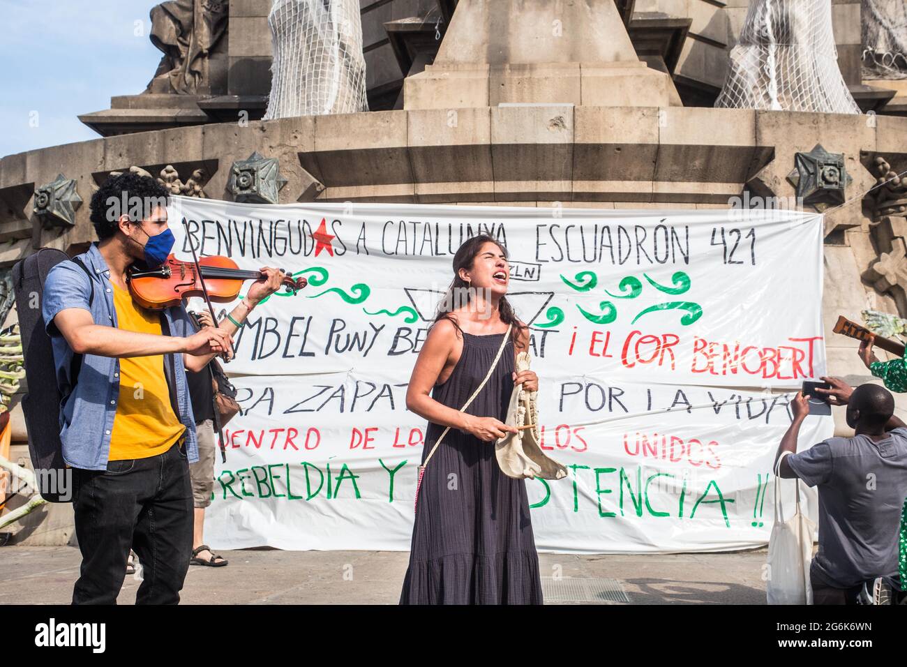 Barcelona, Spain. 06th July, 2021. People playing musical instruments in front of the Columbus Monument, during the event.Barcelona welcomes the 421 Squadron of the Zapatista Army of National Liberation (EZLN), a libertarian socialist political and militant group of Mexico, on their way through Europe. Composed of different members. The 421 Squad has been received at the Columbus Monument by local collectives and social organizations. Credit: SOPA Images Limited/Alamy Live News Stock Photo