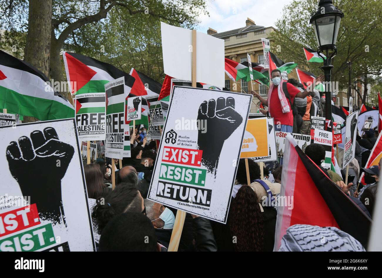 Protesters hold flags and placards expressing their opinion during the demonstration. Pro Palestinian protesters gather outside Downing Street to protest against Palestinian families being evicted from their homes by Jewish settlers in the Sheikh Jarrah district of East Jerusalem. The protesters are also demonstrating about Israeli bombing of civilians in Gaza. Stock Photo