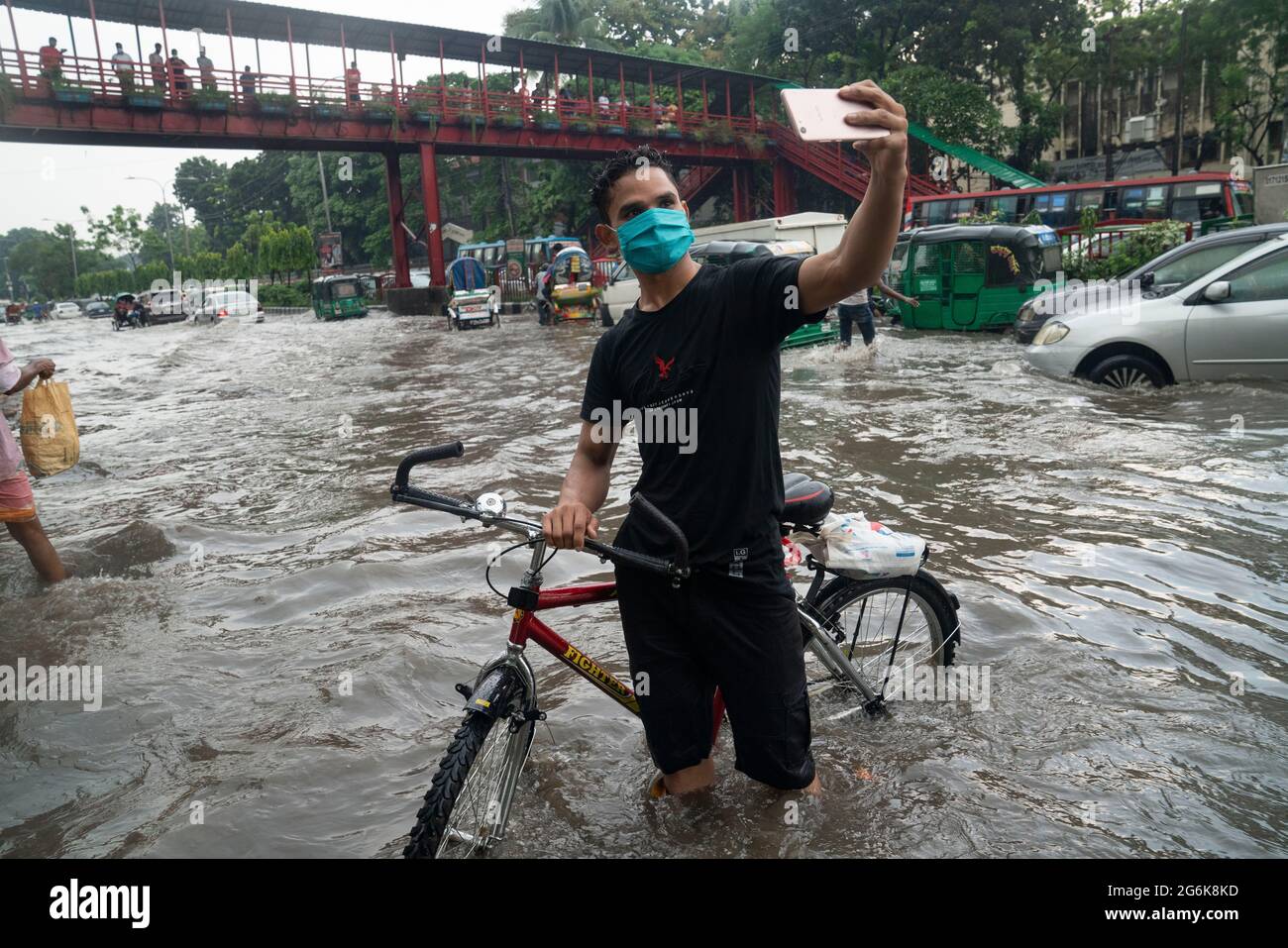 A man takes selfies in rain water on the streets during the monsoon rain. Couple of hours of rain create waterlogging on the streets as the sewerage and drains system is not cleared and maintained properly. Dhaka, Bangladesh. Stock Photo