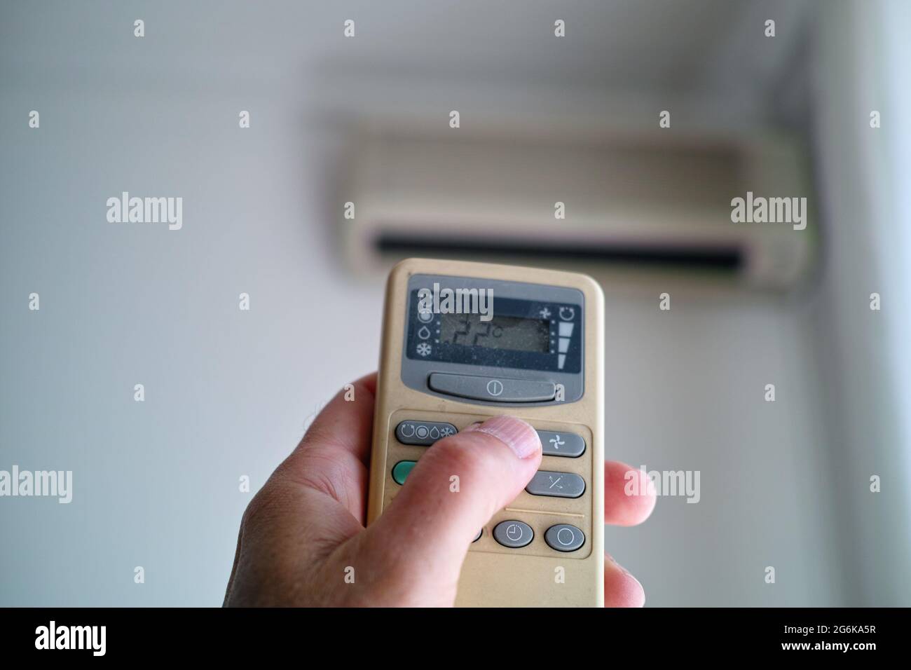 Closeup of a hand with air conditioner remote setting comfortable temperature in a room Stock Photo