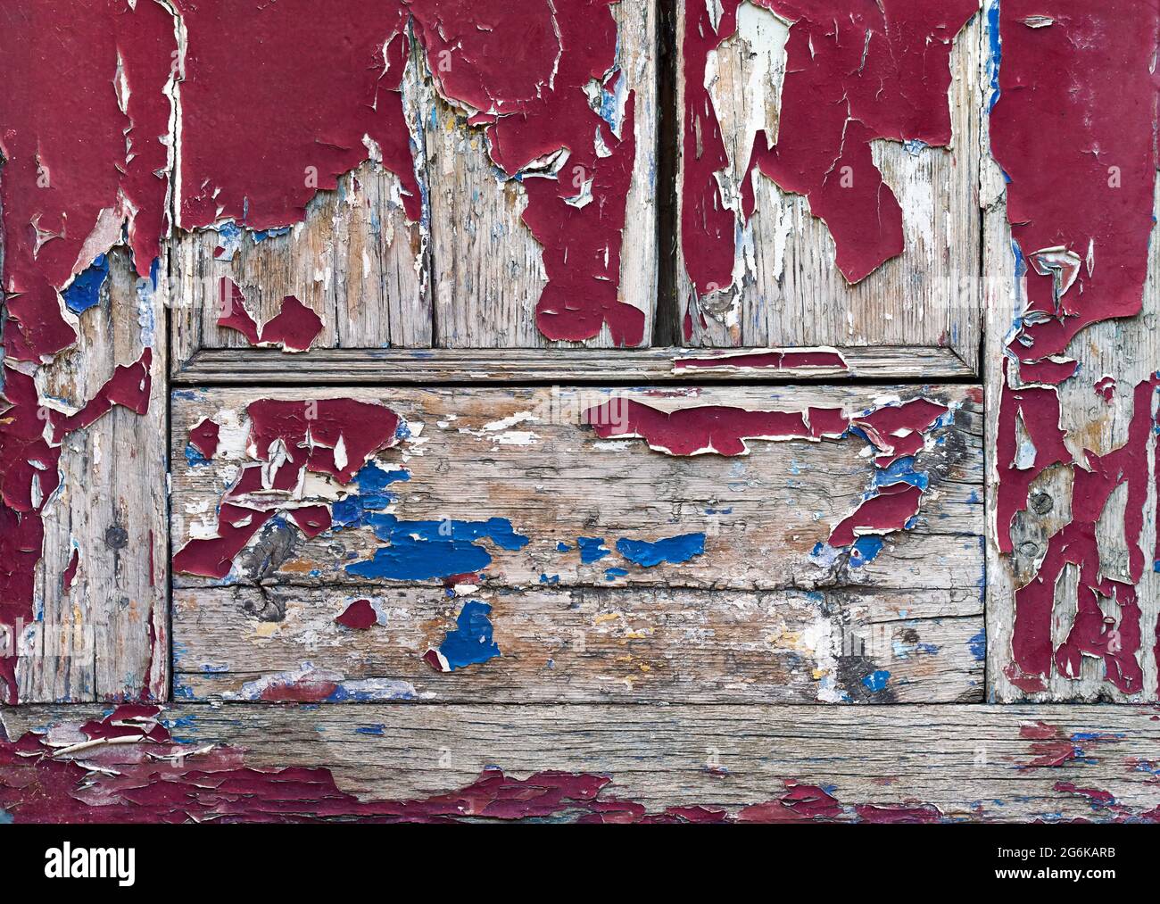 Old red paint cracks and peels away from old grey wood Stock Photo