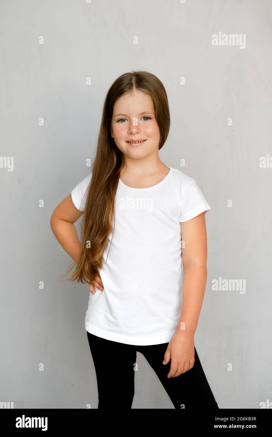 Cute young child with long hair in white t-shirt and black sweatpants posing Stock Photo