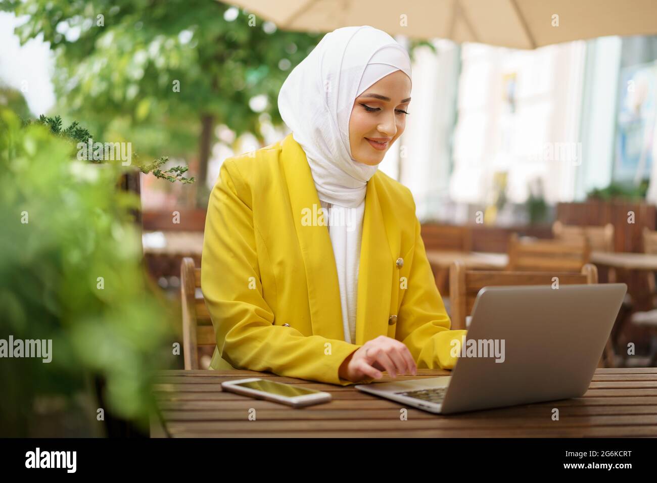 Beautiful smiling muslim woman with laptop at cafe Stock Photo - Alamy