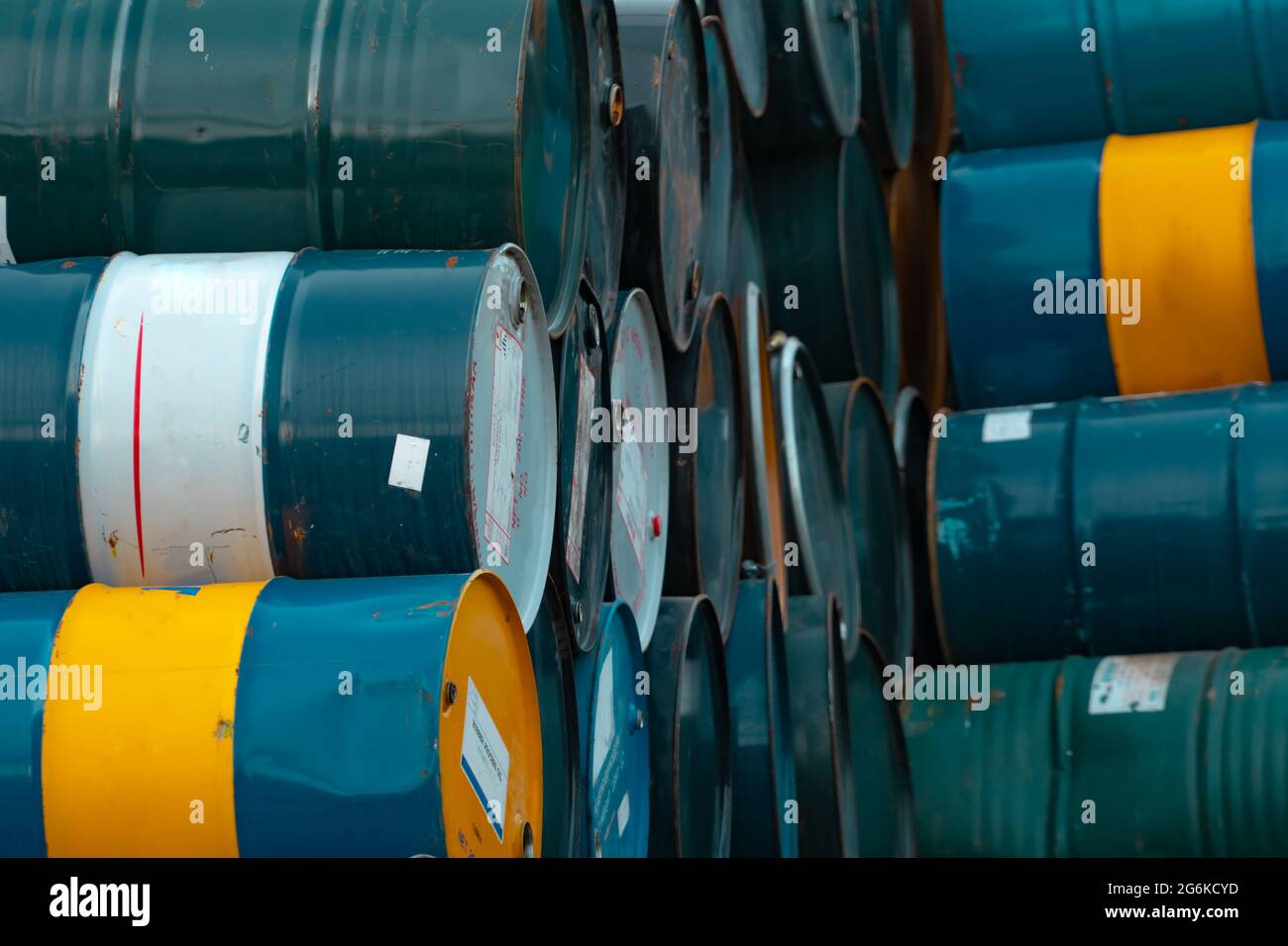 Old chemical barrels stack. Blue, green, and yellow chemical drum. Steel tank of flammable liquid. Hazard chemical barrel. Industrial waste. Empty Stock Photo