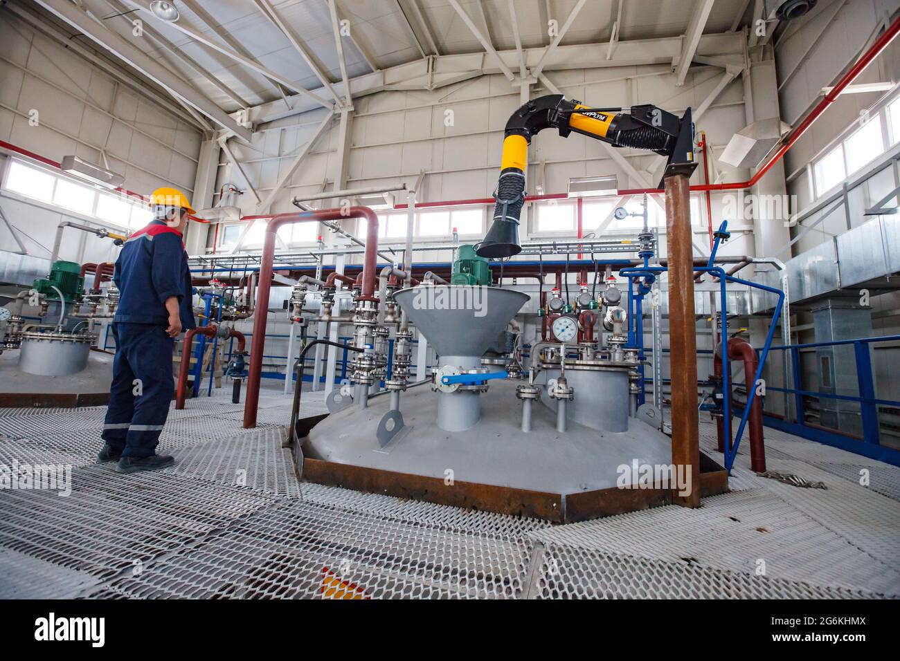 Atyrau,Kazakhstan-May 21,2012: Rauan Nalco chemical plant . Worker adjusting equipment.  Fume extractor (dust collector) arm with hood. Grey metal fun Stock Photo