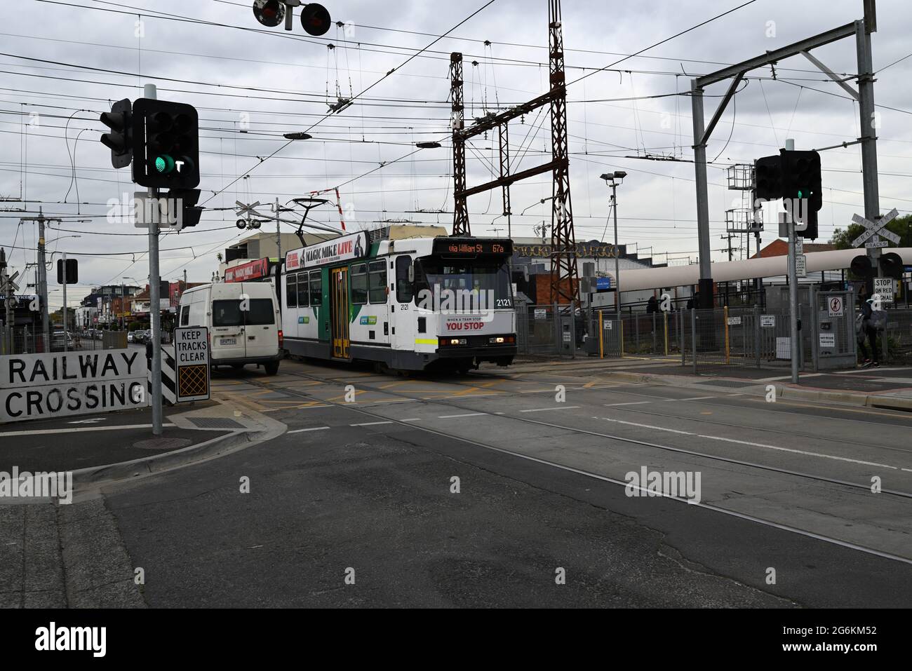 A city-bound B-Class  tram on route 67a, operated by Yarra Trams, crosses the Glen Huntly Rd level crossing next to Glenhuntly Station Stock Photo