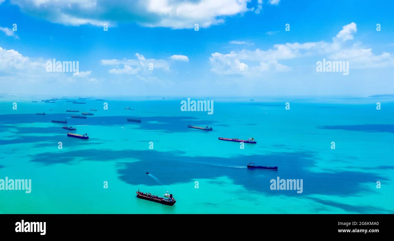 Aerial view of container ships in Singapore Strait. Airplane shot. Cargo ships anchored in the road, waiting to enter the busiest port in region.  Stock Photo