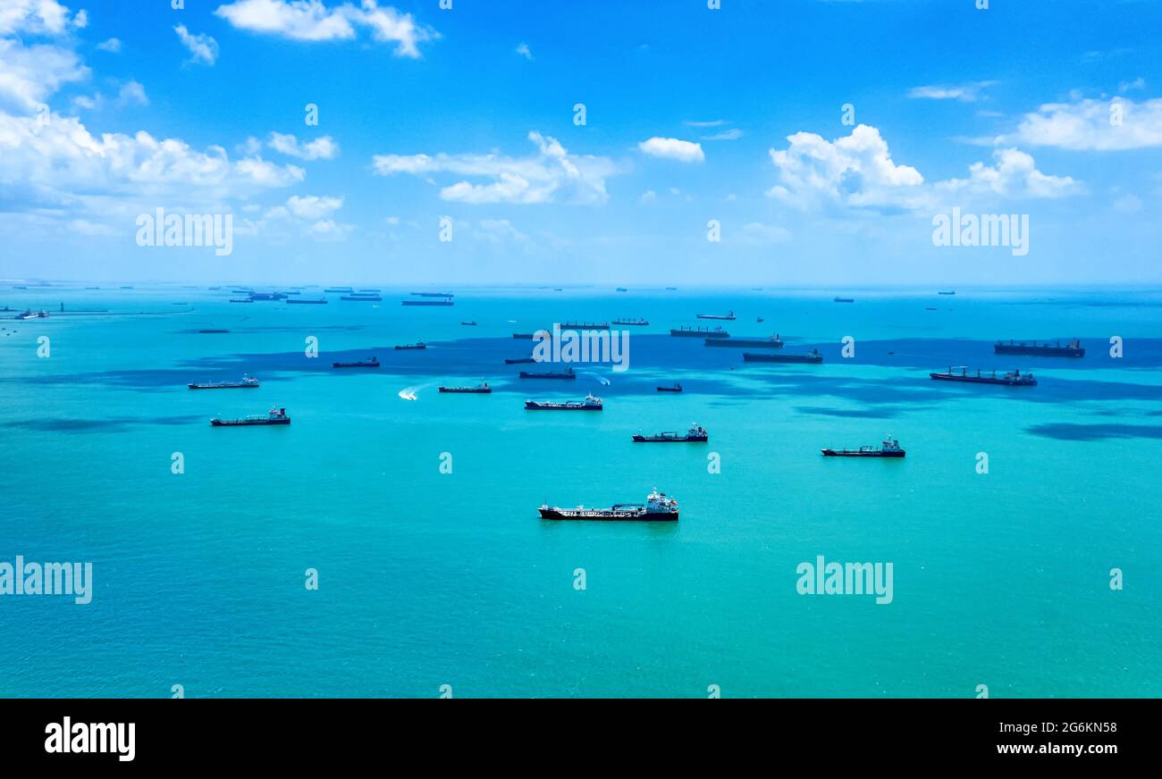 Aerial view of container ships in Singapore Strait. Airplane shot. Cargo ships anchored in the road, waiting to enter the busiest port in region.  Stock Photo