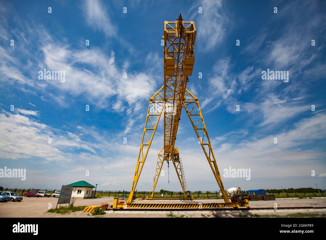 Power yellow gantry crane against scenic blue sky with white clouds. Stock Photo