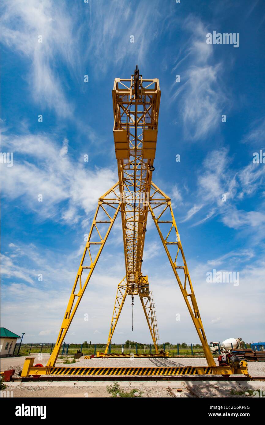 Yellow gantry crane against scenic blue sky with white clouds. Stock Photo