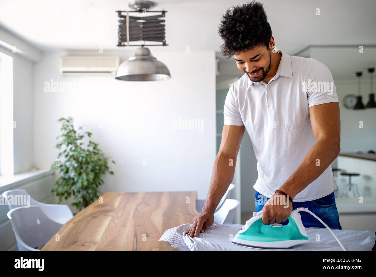 Happy young handsome black man ironing clothes at home Stock Photo