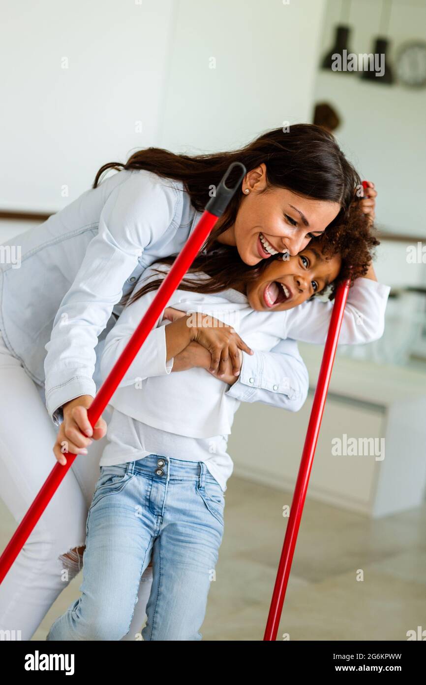 Happy multiethnic family cleaning house and having fun. Children helping mother tidy up the flat. Stock Photo