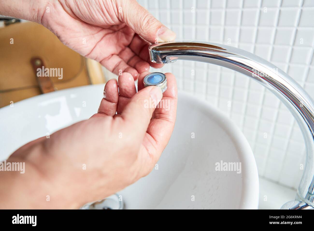 Plumber mounts clean aerator on the faucet in the bathroom after descaling Stock Photo