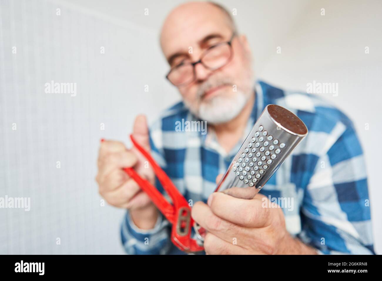 A plumber as a craftsman or do-it-yourselfer repairs shower head with a pipe wrench Stock Photo