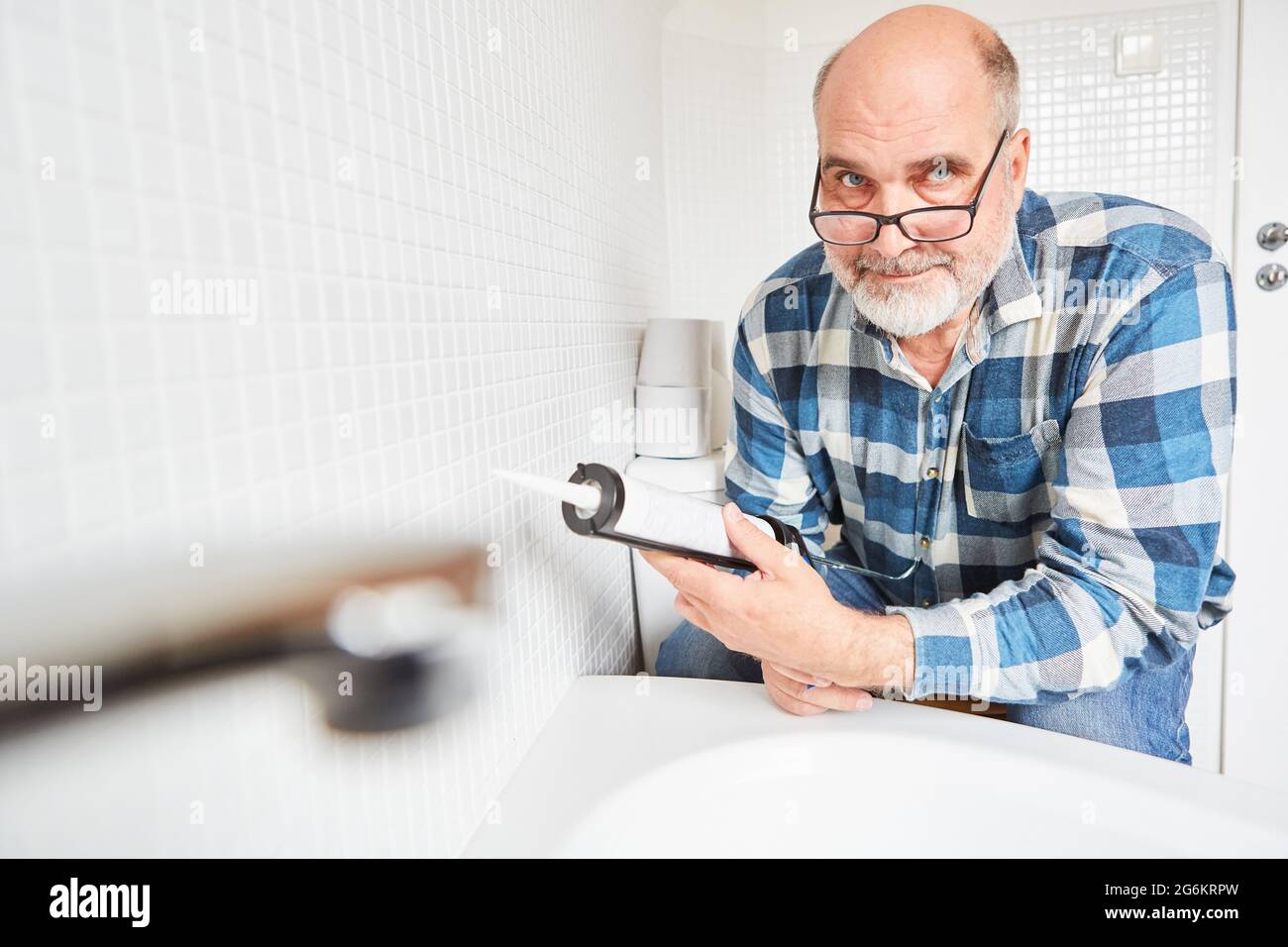 Craftsman or do-it-yourselfer with a cartridge press when sealing joints in the bathroom Stock Photo