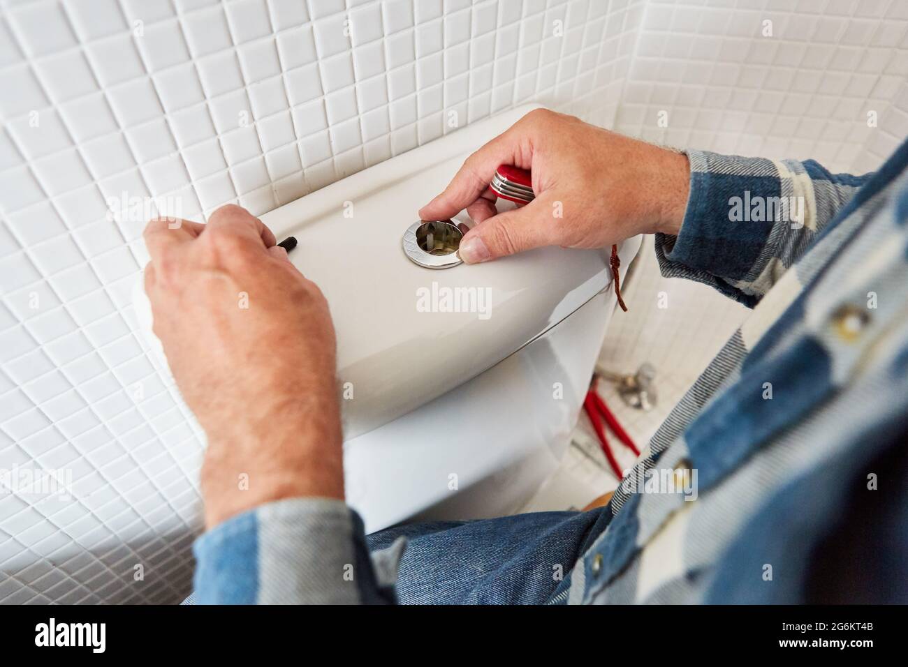 Hands of plumber craftsman install spare part in the defective toilet cistern Stock Photo