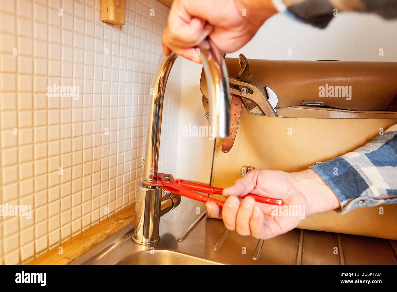 Plumber handyman with pipe wrench when installing faucet on the kitchen sink Stock Photo