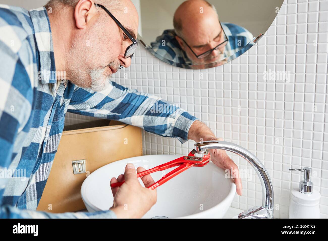 Handyman plumber repairs broken faucet on bathroom sink Stock Photo Alamy