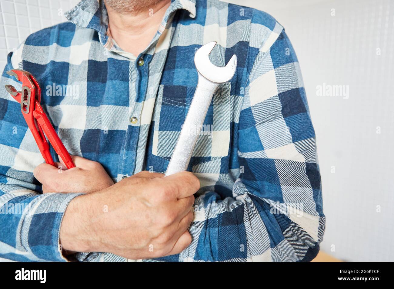 Craftsman with pipe wrench and wrench as a symbol of craftsmanship and competence Stock Photo