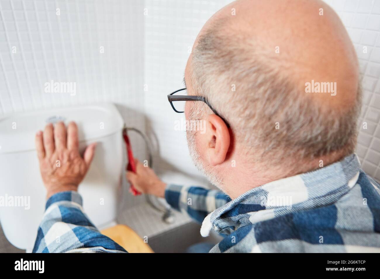 Plumber or do-it-yourselfer repairs or installs toilet cistern in the toilet Stock Photo